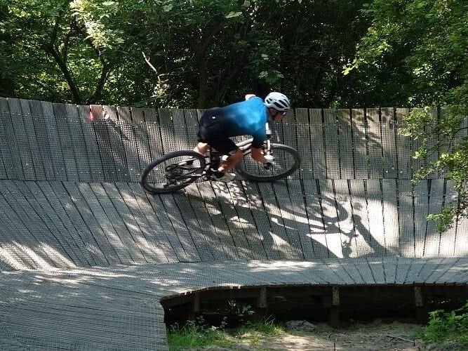 Mountainbiker op een houten steilwand in het bos