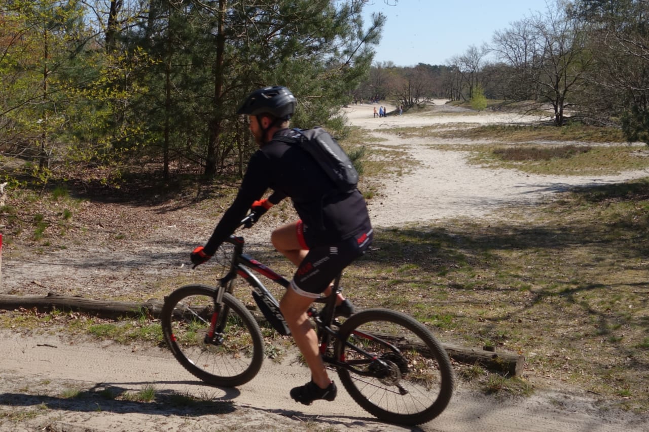 Maat mountainbike bepalen: mountainbiker van opzij op een zandpad bij Dorst, waarop je ziet hoe de rijder op de mountainbike zit