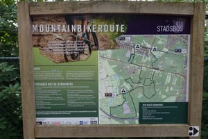 Informatiebord met routekaart en regels van de mountainbikeroute Stadsbos013 bij een startpunt