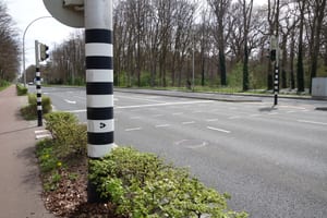 Oversteek van een brede weg op de MTB route Tilburg, met het mountainbike teken op de verkeerspaal
